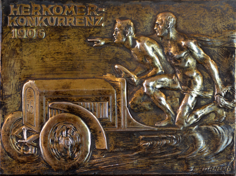 Rechteckige Plakette der Herkomer Konkurrenz 1906 mit Darstellung eines fahrenden Autos mit zwei nackten Männern.
